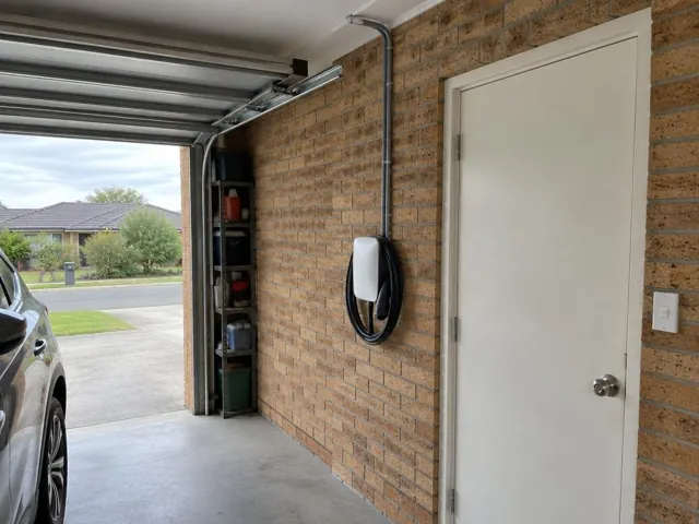 Wall-mounted EV charger on a brick garage wall beside a white door in Aberglasslyn